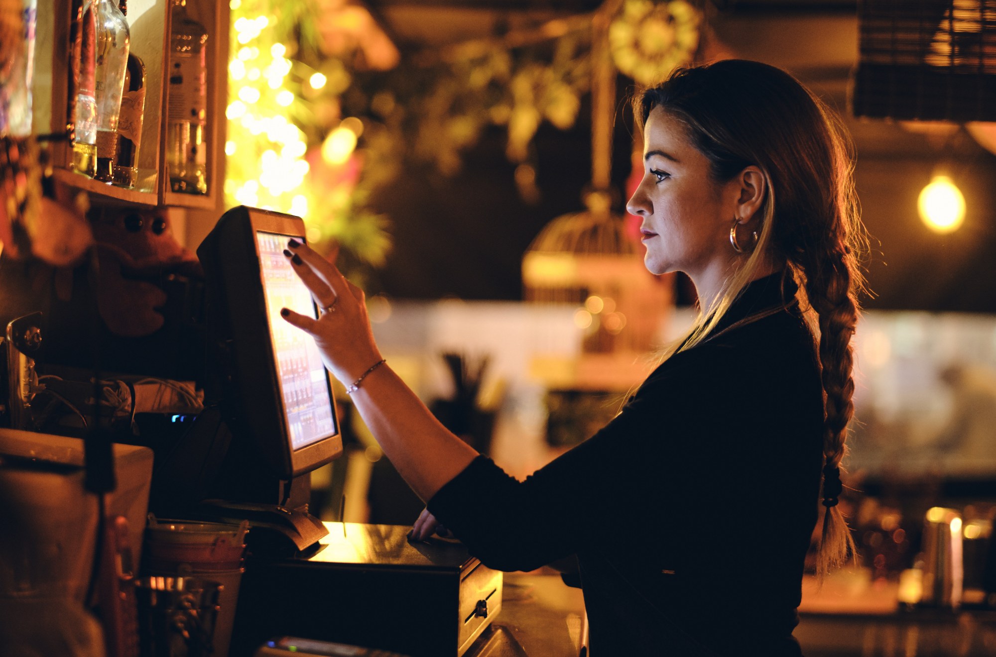young waitress at a bar entering an order into the pos system